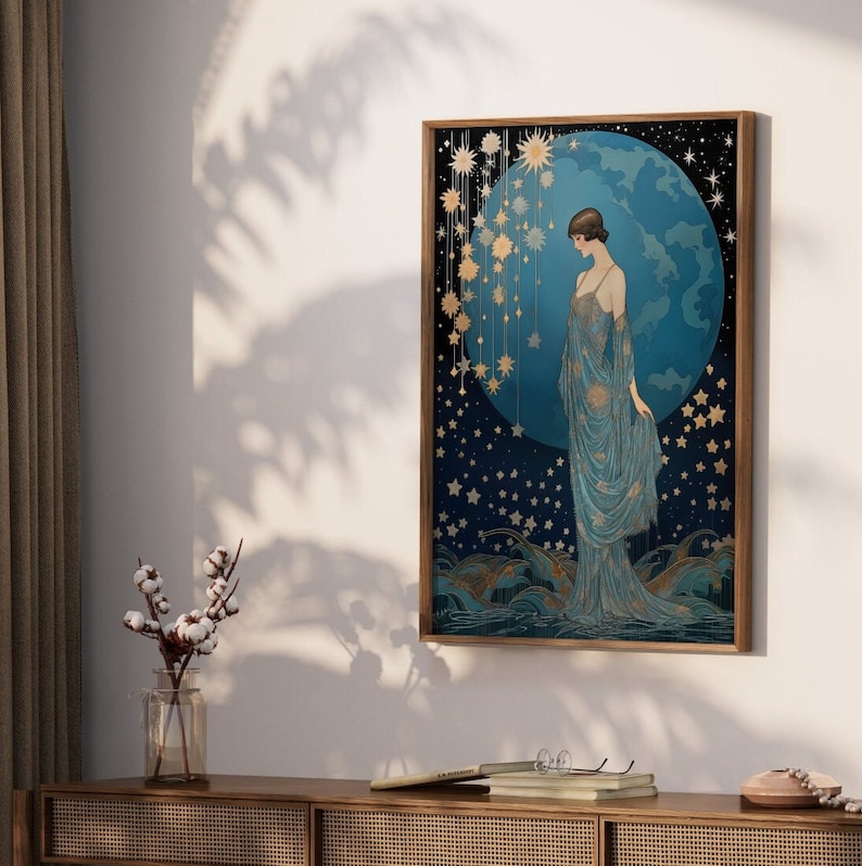 May include: A framed art print featuring a woman in a blue gown standing in front of a blue and gold celestial scene. The scene includes a large blue orb with gold stars and a constellation of smaller stars.