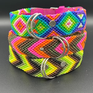 May include: Three colorful dog collars stacked on top of each other. The top collar is a vibrant mix of pink, blue, green, and yellow geometric patterns. The middle collar has a brown, orange, and pink chevron design. The bottom collar has a green, yellow, and brown chevron design.
