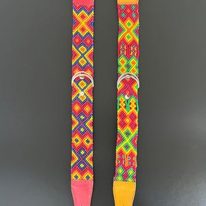 May include: Two colorful dog collars with intricate woven patterns. One collar is red with a red leather backing, and the other is yellow with a yellow leather backing. Both have silver metal hardware.