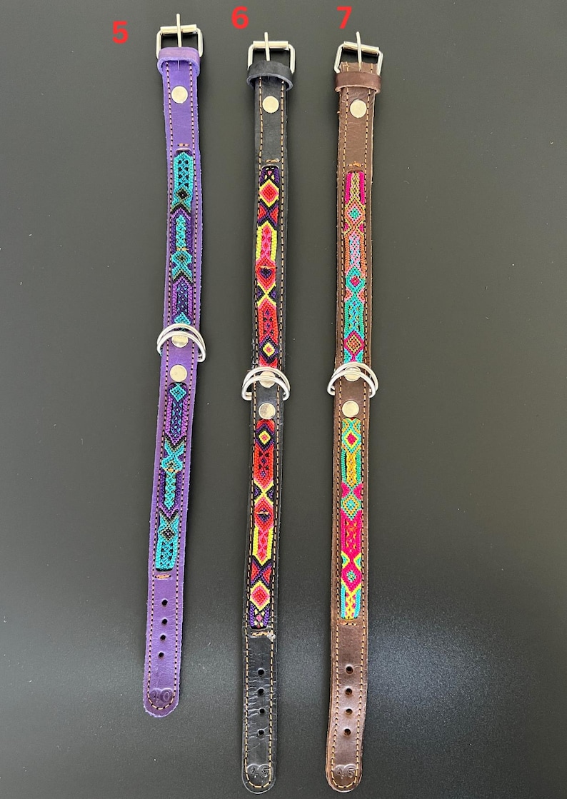 May include: Three dog collars with beaded designs. The collars are purple, black, and brown. Each collar has a silver-colored metal buckle and a D-ring. The beaded patterns feature geometric shapes in various colors, including turquoise, red, yellow, and pink.