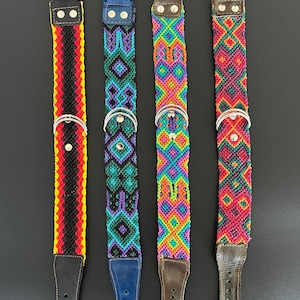 May include: Four colorful dog collars with woven designs. Each collar features a different pattern and color scheme, including red, black, yellow, blue, green, purple, orange, and pink. The collars have metal buckles and leather accents.