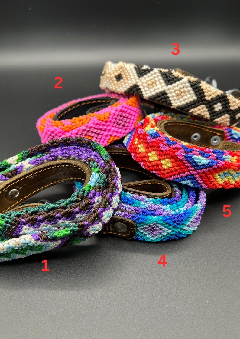 May include: A collection of colorful woven dog collars with leather backing and metal hardware. The collars feature various patterns and color combinations, including purple, blue, green, pink, red, and black and white. The collars are displayed on a dark background.