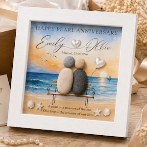 May include: A square white framed wall art piece featuring a pebble art scene of two figures sitting on a bench by the sea. The text reads HAPPY PEARL ANNIVERSARY, Emily and Ollie, Married, 25.05.1996, and A pearl is a treasure of the sea.
