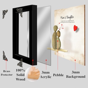 May include: A framed art print with a pebble art design of a mother and daughter. The print has a white background with the text "Mum & Daughter" and a red heart. The frame is made of black wood with a brass protector and a 3mm acrylic layer. The print is mounted on a 3mm wood backing.