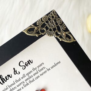 May include: A black picture frame with an ornate gold corner piece. The frame contains a white card with the text "Mother & Son" and a quote about the special bond between a mother and son.
