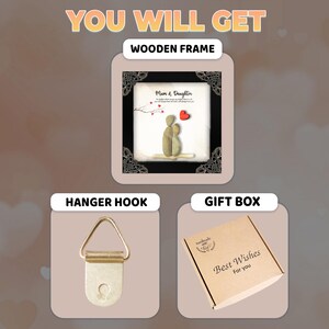 May include: A framed pebble art picture with a black frame and a white mat. The picture shows two figures made of pebbles, representing a mother and daughter. The text "Mum & Daughter" is printed on the mat. The picture comes with a hanger hook and a gift box with the text "Best Wishes For You".