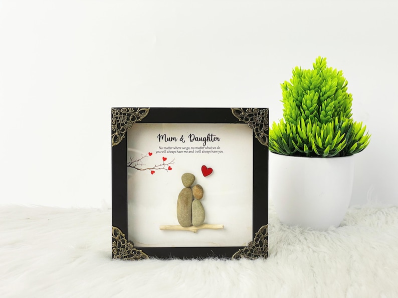May include: A black framed picture with a white background and a quote about mothers and daughters. The quote reads "No matter where we go, no matter what we do you will always have me and I will always have you". The picture features a pebble art design of two figures, a mother and daughter, with red hearts.