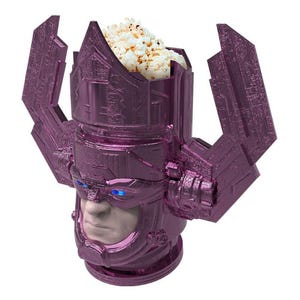 May include: A purple popcorn container shaped like a character's head. The container has a detailed face and headpiece, and is filled with popcorn. The container is designed to hold popcorn.