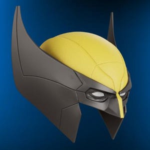 May include: A Wolverine mask featuring a yellow headpiece and dark gray accents. The mask has pointed ears and eye openings, with a distinctive facial design. The overall design is a stylized representation of the character's iconic look.
