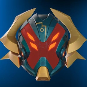 May include: A futuristic helmet design with a teal and red color scheme, accented by gold-colored details. The helmet features glowing orange eye-like shapes and angular gold side pieces, creating a striking, stylized appearance.