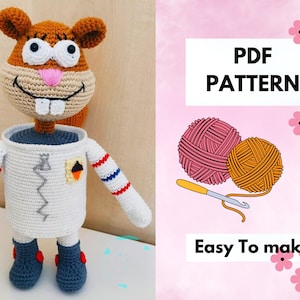 Puede incluir: Patrón de crochet para una ardilla marrón y tostada que lleva un traje de astronauta blanco con rayas azules y rojas. El patrón incluye una descarga PDF y es fácil de hacer. La imagen también muestra dos ovillos de lana y un gancho de crochet.