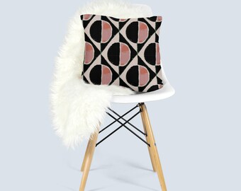 Puede incluir: Una silla blanca con patas de madera y un cojín de decoración con estampado geométrico negro y rosa.