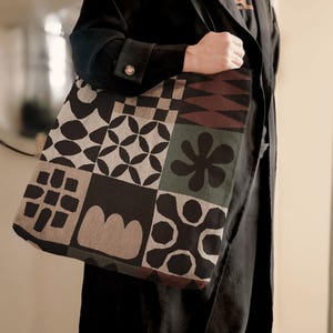 Peut inclure: Un sac fourre-tout noir et blanc avec un motif géométrique. Le sac a un design brun, vert et noir avec une variété de formes et de motifs.