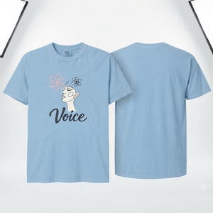 以下が含まれることがあります： ライトブルーの半袖Tシャツ。前面には人間の横顔の線画と頭上の2つの原子記号、そしてダークカラーの筆記体でVoiceという文字がプリントされており、隣には無地の背面図が並んでいます。