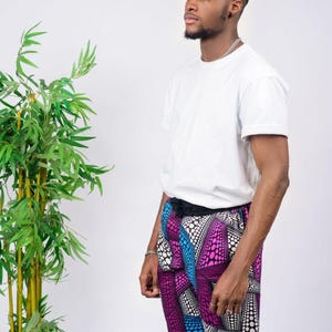 Op de afbeelding: Een effen wit T-shirt met korte mouwen gecombineerd met een knielange short met een levendig geometrisch patroon in tinten paars, blauw, zwart en wit. De short heeft een zwarte tailleband en een herhalend patroon van stippen en lijnen.