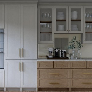 May include: A modern kitchen design featuring white cabinetry with gold hardware, a built-in microwave and oven, and a light wood base cabinet. Glass-fronted upper cabinets display dishware and glassware. A coffee station sits on the countertop.