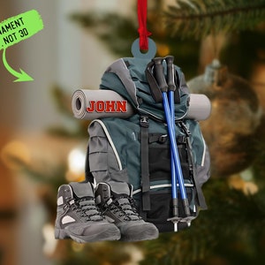 Puede incluir: Una mochila gris y azul con bastones de senderismo, una esterilla enrollada y botas de senderismo. La mochila tiene el nombre "JOHN" impreso en ella.