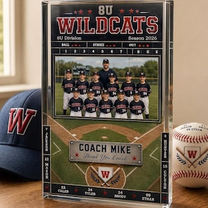 May include: A clear acrylic baseball team photo frame featuring the text "8U Wildcats" and "Season 2026". The frame includes a team photo, a baseball field graphic, and the text "Coach Mike Thank You Coach". A baseball and a baseball cap are also visible.