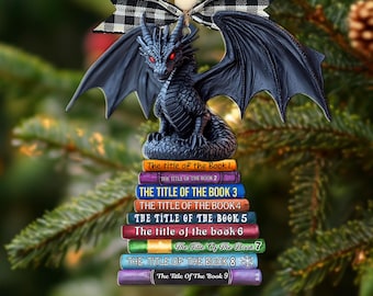 May include: A black dragon Christmas ornament with red eyes, perched atop a stack of colorful books. The books are labeled "The Title of the Book" followed by numbers. The ornament is suspended by a string and a black and white checkered bow.