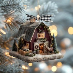 May include: A miniature Christmas ornament shaped like a red barn with a snowy roof and a black and white checkered bow. The barn features a horse, hay bales, and small Christmas trees. The ornament is suspended by a gold string.