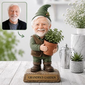 Op de afbeelding: Een gepersonaliseerd beeldje van een oudere man met een witte baard, een groene hoed, een groen overhemd en een bruin vest, die een terracotta pot met een groene plant vasthoudt. Het beeldje staat op een voetstuk met de tekst GRANDPA'S GARDEN.
