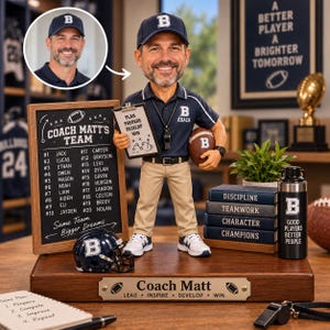 May include: A custom bobblehead of a coach wearing a navy blue polo shirt, khaki pants, and a navy cap with a B. The figure holds a clipboard with Plan Prepare Develop Win text and a football. It stands on a wooden base with a Coach Matt plaque.