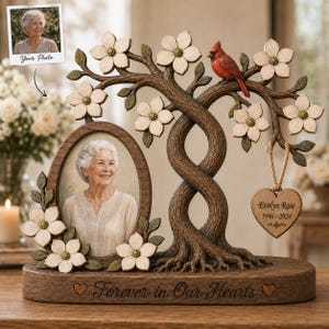 May include: A memorial tree sculpture featuring an oval photo frame, white dogwood flowers, and a red cardinal. A heart-shaped wooden tag hangs from a branch with the text Evelyn Rose 1946-2024. The base is inscribed with Forever in Our Hearts.