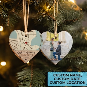 May include: A heart-shaped wooden ornament with a map on one side and a photo on the other. The map side shows a location with the text "Josh & Summer Engaged 11.26.2022". The photo side shows a couple getting engaged.