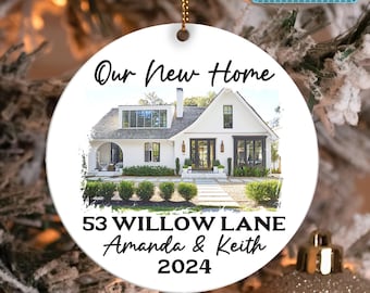 May include: White ceramic ornament with a photo of a white house with a black door and green bushes. The text "Our New Home" is at the top, and the text "53 Willow Lane Amanda & Keith 2024" is at the bottom.