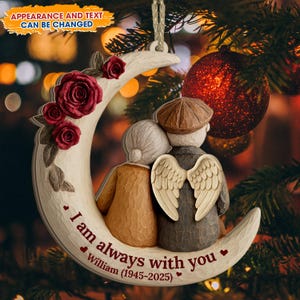 Può includere: Un ornamento natalizio a forma di mezzaluna intagliata con una coppia che si abbraccia. L'ornamento presenta rose rosse e il testo "I am always with you William (1945-2025)". La coppia ha ali d'angelo. Il testo "APPEARANCE AND TEXT CAN BE CHANGED" è in alto.