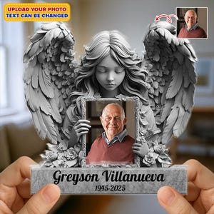 Könnte beinhalten: Eine graue Engelsstatue, die ein gerahmtes Foto eines älteren Mannes hält. Die Statue hat große Federflügel und einen ruhigen Ausdruck. Auf dem Sockel der Statue stehen der Name "Greyson Villanueva" und die Jahreszahlen "1945-2025". Der Text "UPLOAD YOUR PHOTO TEXT CAN BE CHANGED" steht oben.