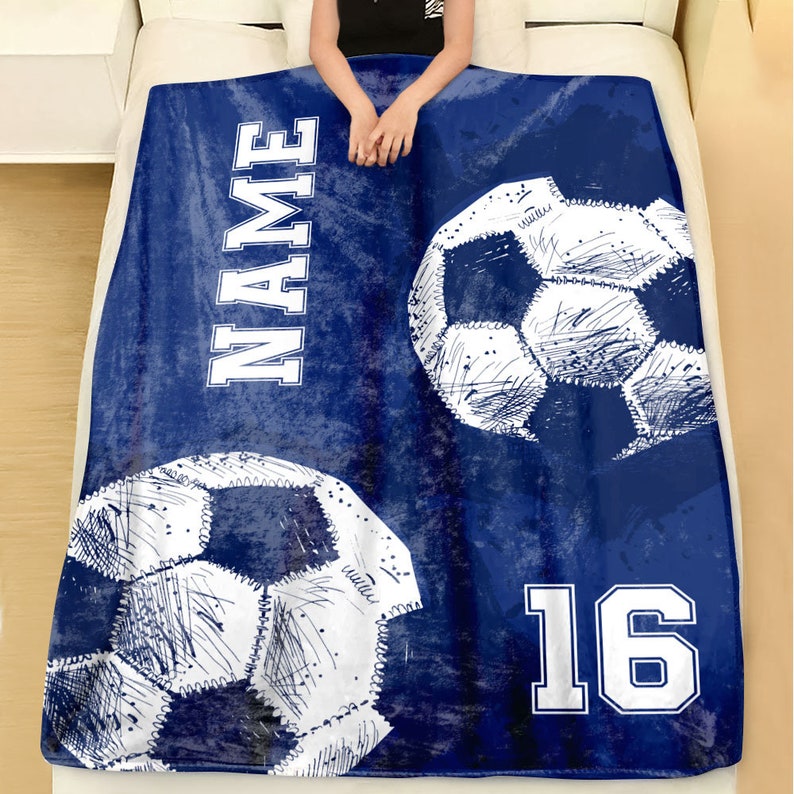 May include: Blue fleece blanket with a white soccer ball design, the word "NAME" and the number "16" in white.