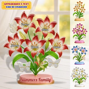 Könnte beinhalten: Ein personalisiertes Blumenarrangement mit rot-weißen Lilien mit Namen auf den Blütenblättern. Auf dem Sockel steht "Summers Family". Enthält dekorative Schmetterlinge. Der Text "APPEARANCE & TEXT CAN BE CHANGED" befindet sich oben links. Zusätzliche Blumenarrangements.