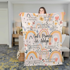 May include: A cream-colored blanket featuring pastel rainbows, flowers, and hearts. The blanket has the text "God's Promises for Adalyn" and inspirational phrases. The design includes soft colors like peach, blue, and yellow.