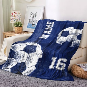 May include: Blue fleece blanket with a white soccer ball design and the text "NAME" and "16".