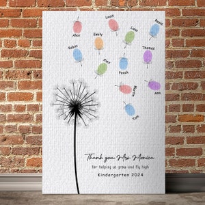 May include: A white canvas with a black dandelion illustration and colorful handprints with names around it. The text reads "Thank you Mrs. Monica for helping us grow and fly high Kindergarten 2024".