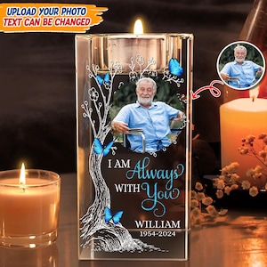 May include: A clear glass candle holder with a photo of a person, butterflies, and the text "I Am Always With You William 1954-2024". The candle holder has a silver-coloured top with a lit candle.