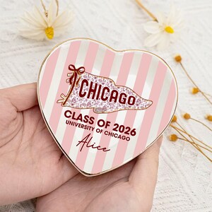 Puede incluir: Plato para baratijas en forma de coraz&oacute;n con rayas rosas y blancas. El plato presenta la palabra "CHICAGO" en un dise&ntilde;o estilizado, junto con "CLASS OF 2026 UNIVERSITY OF CHICAGO" y el nombre "Alice". El plato tiene un borde dorado.