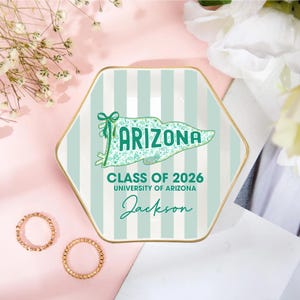Puede incluir: Una bandeja hexagonal de cer&aacute;mica con borde dorado y fondo a rayas verde menta y blanco. La bandeja presenta la palabra "ARIZONA" en un dise&ntilde;o de pancarta, junto con "CLASS OF 2026", "UNIVERSITY OF ARIZONA" y el nombre "Jackson".