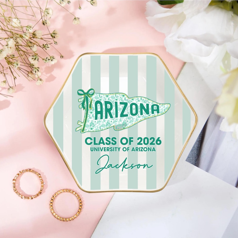 Puede incluir: Una bandeja hexagonal de cer&aacute;mica con borde dorado y fondo a rayas verde menta y blanco. La bandeja presenta la palabra "ARIZONA" en un dise&ntilde;o de pancarta, junto con "CLASS OF 2026", "UNIVERSITY OF ARIZONA" y el nombre "Jackson".