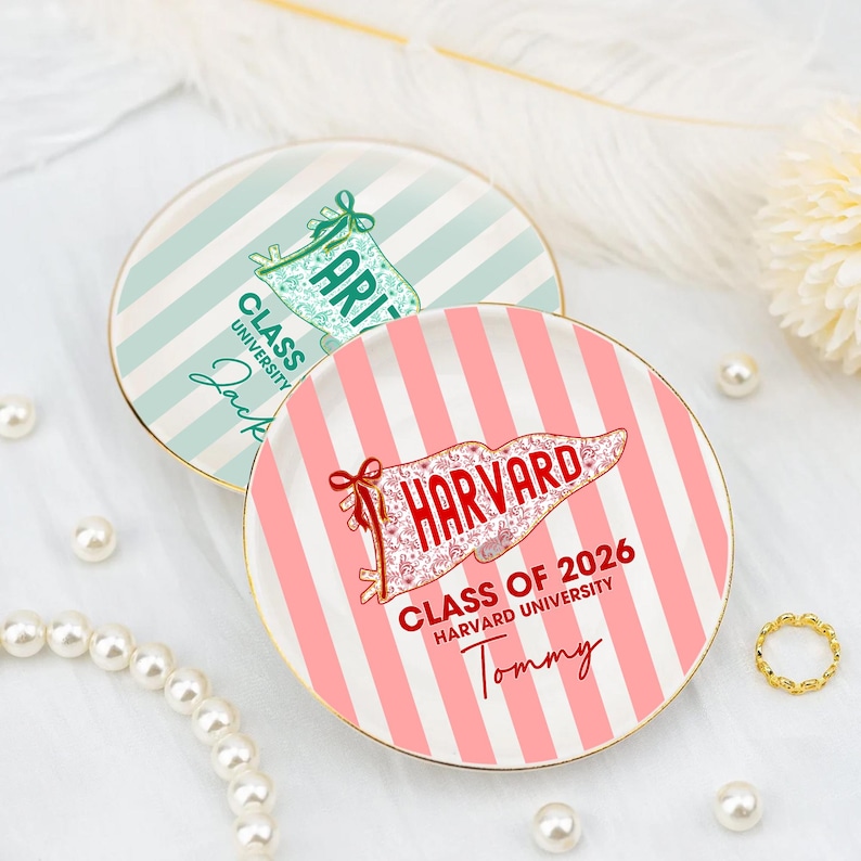 Puede incluir: Dos platos decorativos de cer&aacute;mica con bordes dorados. Uno es a rayas rosas y blancas con el texto "HARVARD" y "CLASS OF 2026". El otro es a rayas verde menta y blanco con el texto "ARIZ". Ambos platos tienen nombres personalizados.