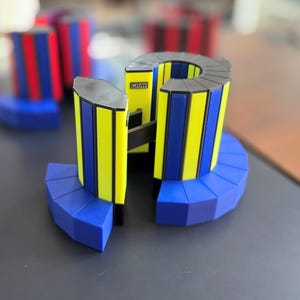 May include: A colorful geometric puzzle with yellow, blue, and black accents. The puzzle has a curved shape with the word "CRAY" visible on the side. Other similar puzzles are in the background.