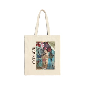 May include: Cream-colored tote bag with a collage design featuring a rose, a portrait, and the word "Copenhagen" in brown vertical text. The bag has two handles and is made of a canvas-like material.