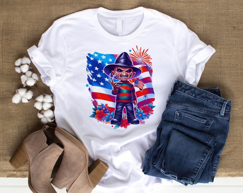 May include: White t-shirt featuring a cartoon character with a hat and striped sweater, holding a flag in front of an American flag design. The shirt is paired with blue jeans and tan ankle boots. The design includes flowers and fireworks.