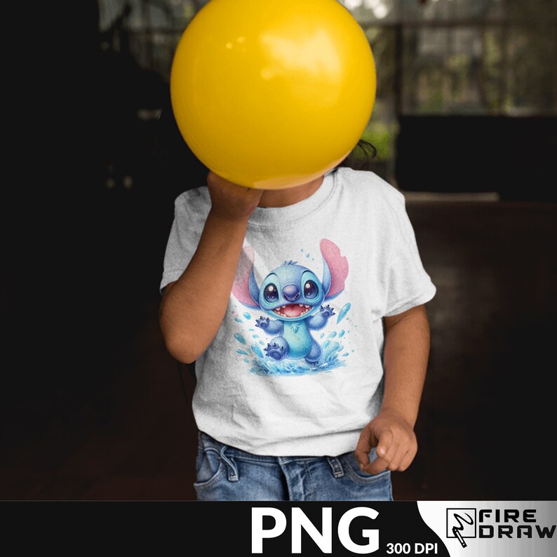 Puede incluir: Una camiseta blanca con un personaje de dibujos animados azul con orejas rosas, ojos azules y una gran sonrisa. El personaje est&aacute; de pie en un charco de agua con salpicaduras azules y blancas. La camiseta est&aacute; siendo sostenida por un ni&ntilde;o.