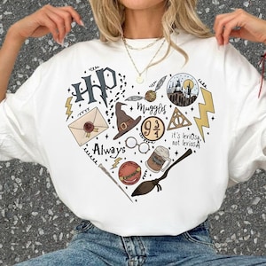 May include: White t-shirt with a heart-shaped graphic featuring Harry Potter-themed illustrations. The design includes a lightning bolt, a letter, a hat, glasses, a broom, and the text "Always" and "Muggles".