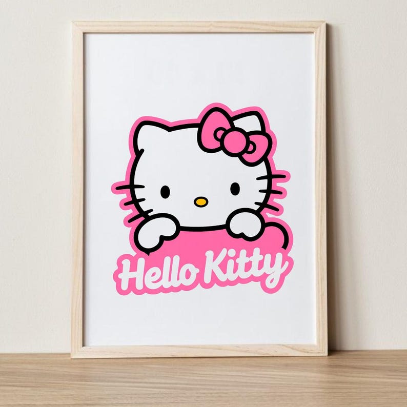 May include: Framed print featuring the iconic Hello Kitty character. The image shows Hello Kitty's white face with a pink bow, black eyes, and whiskers. The words "Hello Kitty" are in pink script below the character.