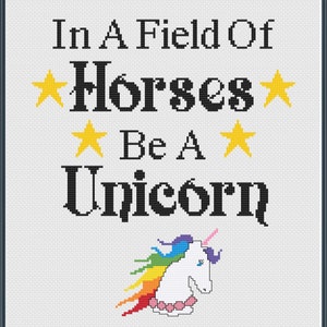 May include: Cross-stitch art with a white background and a black border. The text reads "In A Field Of Horses Be A Unicorn" with yellow star accents. A white unicorn with a rainbow mane and pink horn is at the bottom.