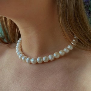 May include: A classic white pearl necklace. The pearls are round and smooth, and the necklace is a simple and elegant piece of jewellery.