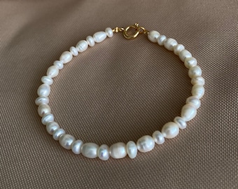 May include: A delicate pearl bracelet with a gold clasp. The bracelet is made of small, white pearls and is perfect for everyday wear.